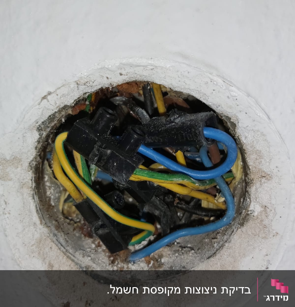 חוטי חשמל צבעוניים בקופסת חיבורים בקיר